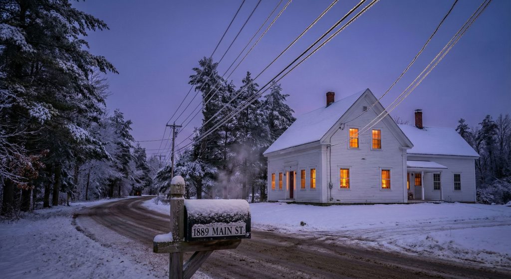 Electricity lines lead to a house in a snowy landscape as rates in Maine increase for January